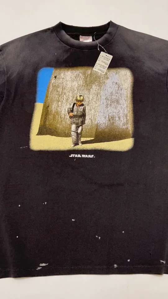 SAINT Mxxxxxx × STAR WARS SW_SS TEE /ANAKIN/BLK Star Wars co-branded TEE Anakin Skywalker Darth Vader reflection print TEE washed black S-XL The print comes from the impressive poster vision of "Anakin Skywalker" in "STAR WARS Episode I/The Phantom Menace" and the design of "Darth Vader" printed on the back The entire garment is hand-processed with dirt, washed with water, and printed with a distressed feel, which perfectly interprets the artistic specialty of NEW VINTAGE. In addition, the main mark and wash mark are customized to be consistent with the original version. It can be said that every detail of ZP is perfectly reproduced.